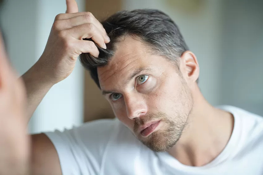 Man kijkend in de spiegel naar zijn haarlijn