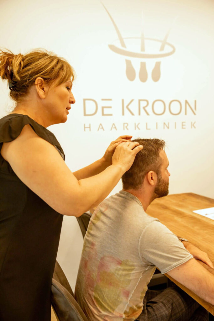 Impressie van een consult bij Haarkliniek de Kroon waarbij een haarspecialiste uitleg geeft over de kruin van de cliënt.